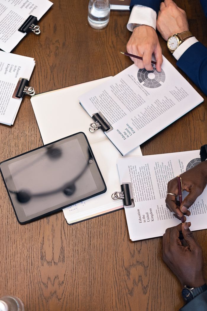 home-services-03 Top view of a business meeting with hands, tablets, and documents on a table.